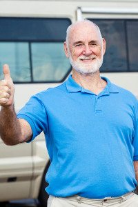 Man Giving a Thumbs Up and Smiling at the Camera while Standing in Front of His Motor Home